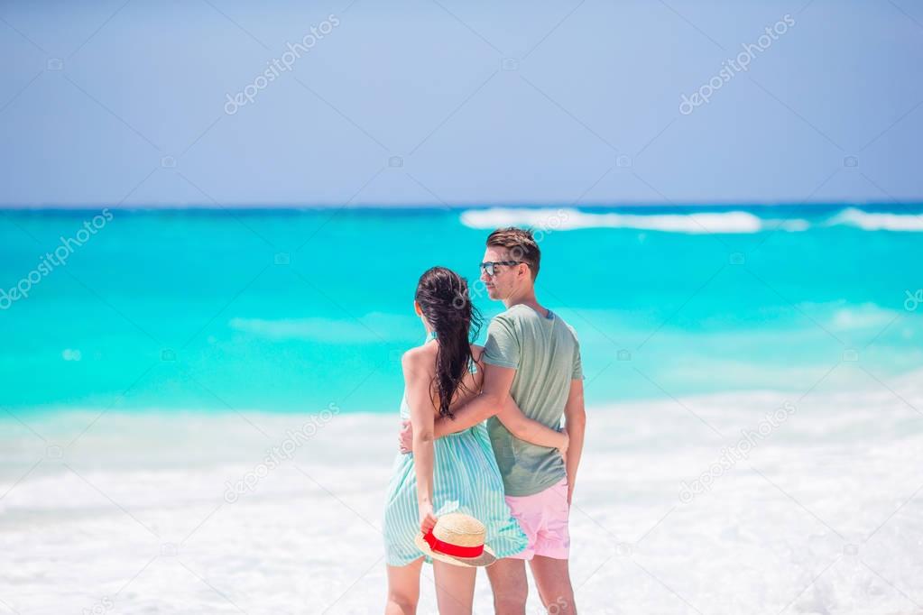 Young couple on white beach during summer vacation. Happy family walking along the ocean