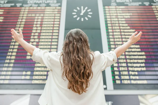 Jovem mulher no aeroporto internacional olhando para a placa de informações de voo verificando se há voo — Fotografia de Stock