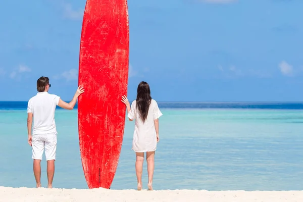 Молодая пара с красной доской для серфинга во время тропических каникул — стоковое фото