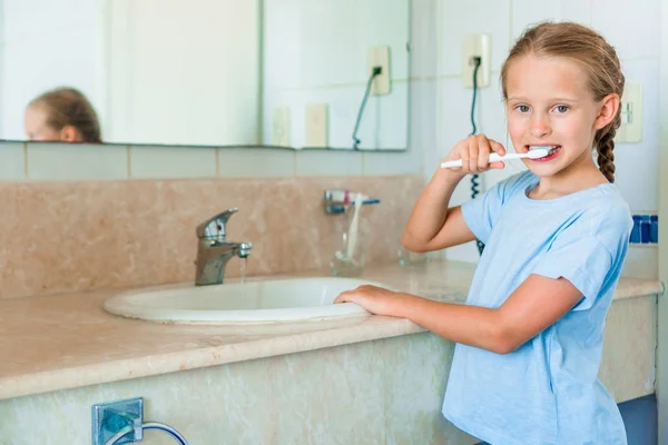 Маленькая улыбчивая девочка чистит зубы в ванной — стоковое фото
