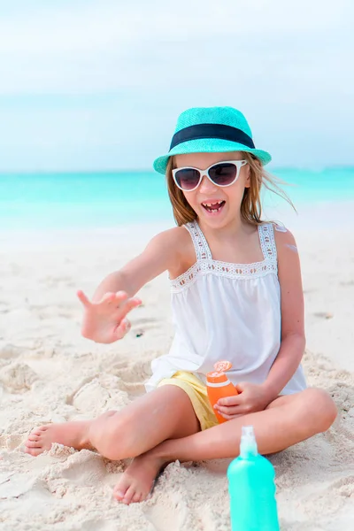 Rozkošná holčička s suncream láhev na pláži — Stock fotografie