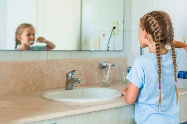 Маленькая красивая девочка с белыми зубами чистит зубы в ванной — стоковое фото