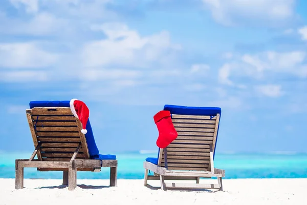 Red Christmas stocking and Santa Hat on beach beds — Stock Photo, Image