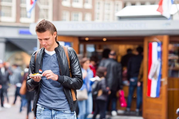Vrolijke Kaukasische toerist met verse haring met uien- en nederlandse vlag in Amsterdam. Traditioneel Hollands eten buiten — Stockfoto