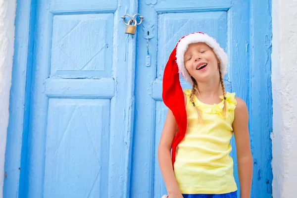 Little girl in santa hat outdoors in the city on Christmas vacation — Stock Photo, Image