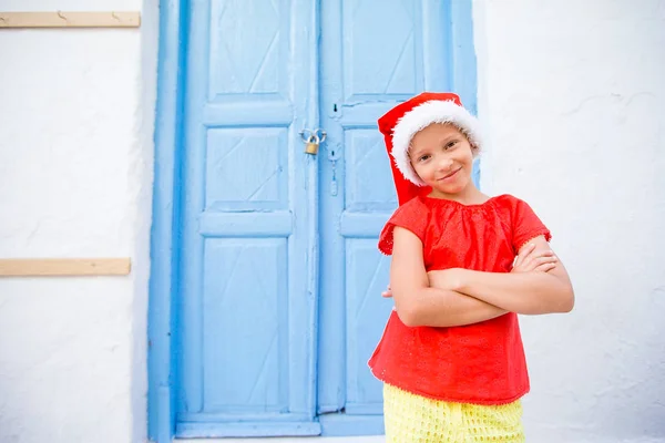 Little girl in santa hat outdoors in the city on Christmas vacation — Stock Photo, Image