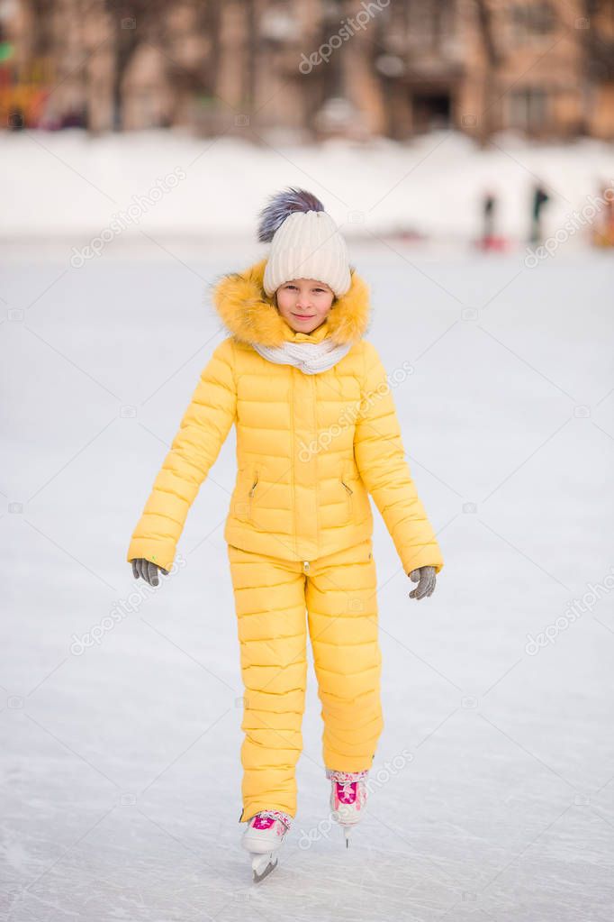 Adorable little girl skating in winter snow day outdoors