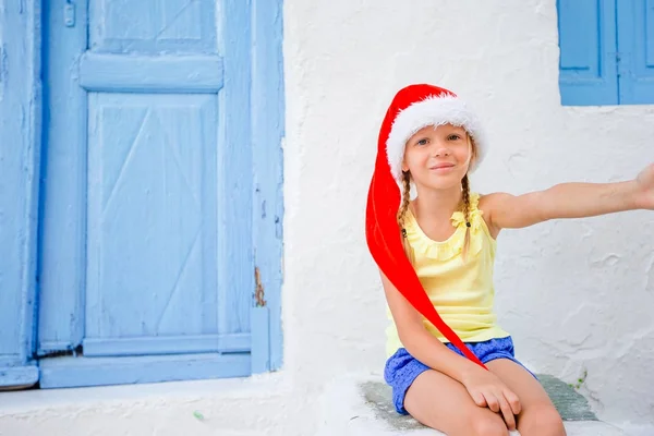 Niña en sombrero de santa al aire libre en la ciudad en vacaciones de Navidad —  Fotos de Stock