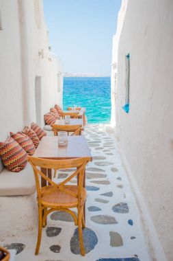 Benches with pillows in a typical greek outdoor cafe in Mykonos with amazing sea view on Cyclades islands clipart