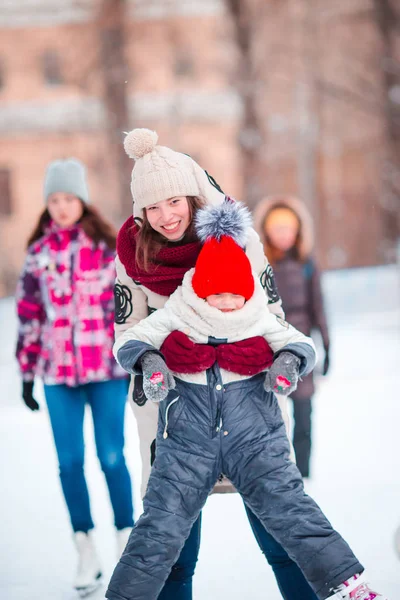Mała, urocza dziewczyna z matką, jazda na łyżwach na lodowisku — Zdjęcie stockowe