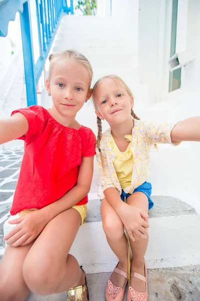 Δύο κοριτσάκια λήψη selfie φωτογραφία σε εξωτερικούς χώρους σε ελληνικό χωριό, στο στενό δρόμο στην Μύκονο — Φωτογραφία Αρχείου