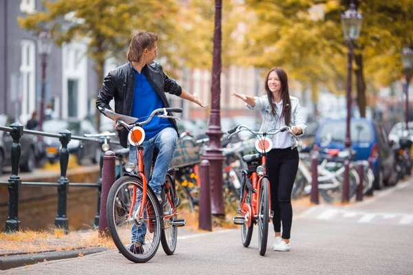 Joven pareja caucásica feliz en bicicletas en las calles antiguas de Amsterdam — Foto de Stock