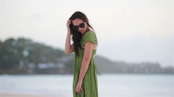 Young beautiful woman on tropical seashore. Tourist girl in green dreess on the beach — Stock Video