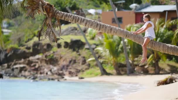 Liten flicka på tropical beach sitter på Palm under sommarlovet — Stockvideo