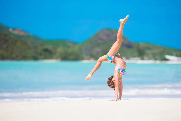 Chica activa en la playa divirtiéndose mucho. Niño deportivo haciendo la rueda en la orilla del mar —  Fotos de Stock