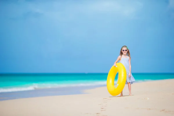 Schattig meisje met opblaasbare rubberen cirkel op witte strand klaar voor zwemmen — Stockfoto