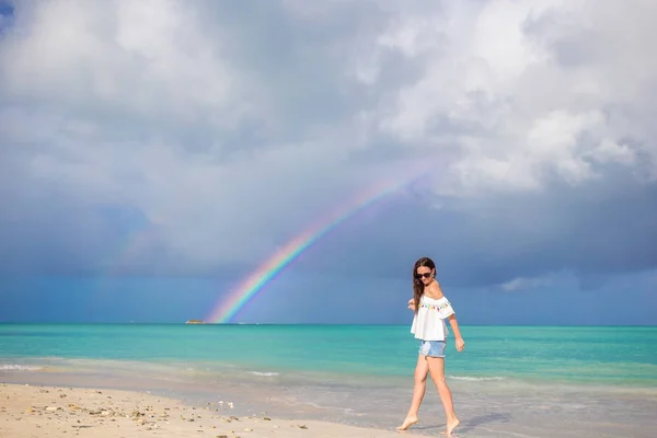 Hermosa mujer feliz en la playa con hermoso arco iris sobre el mar — Foto de Stock