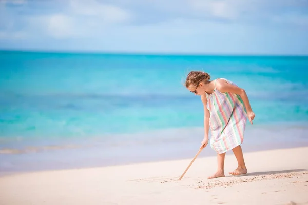 Schattig meisje op strand tijdens zomervakantie puttend uit zand — Stockfoto