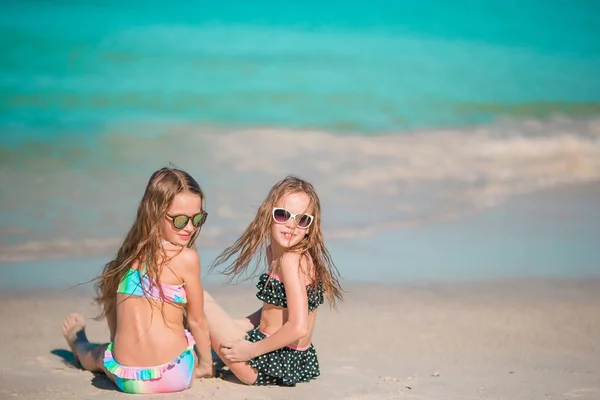 Entzückende kleine Mädchen, die am Strand mit Sand spielen. Kind sitzt im flachen Wasser — Stockfoto