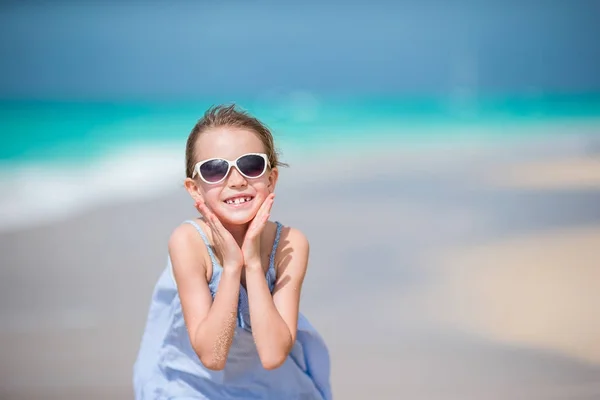 Porträt eines glücklichen, geschmückten Kindes, das auf den Hintergrund der Kamera blickt, wunderschönen Himmel und Meer. kleines Mädchen mit Sonnenbrille lächelt und genießt ihren Urlaub — Stockfoto