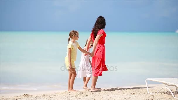 Очаровательные маленькие девочки и молодая мама веселятся на белом пляже — стоковое видео