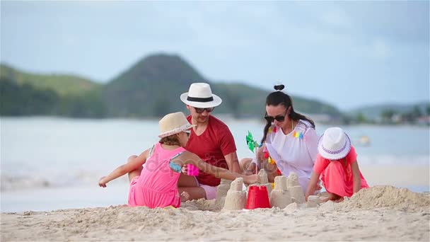 Los padres con niños juegan haciendo castillo de arena en la playa tropical blanca — Vídeo de stock