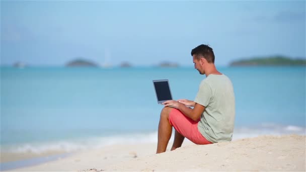 Jovem com laptop na praia tropical caribenha — Vídeo de Stock