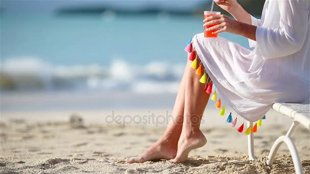 Jonge vrouw met cocktail op witte strand zittend op de zonnebank. Closeup smakelijke cocktail achtergrond de zee — Stockvideo