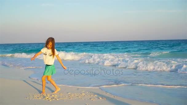 Schattig gelukkig klein meisje op wit strand bij zonsondergang — Stockvideo