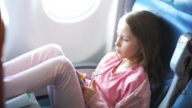 Sevimli küçük kız bir uçakla seyahat. Uçak penceresinde yakınındaki dizüstü bilgisayar ile şirin çocuk