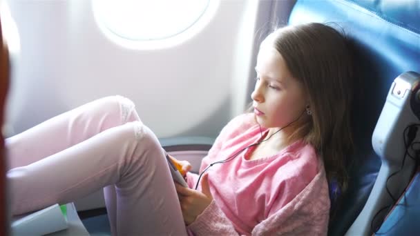 Adorable little girl traveling by an airplane. Cute kid with laptop near window in aircraft — Stock Video