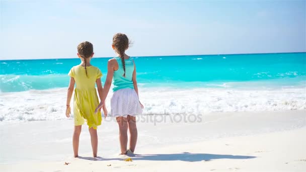 Liebenswerte kleine Mädchen, die am Strand spazieren gehen. Rückansicht der Kinder genießen gemeinsam Meerblick — Stockvideo