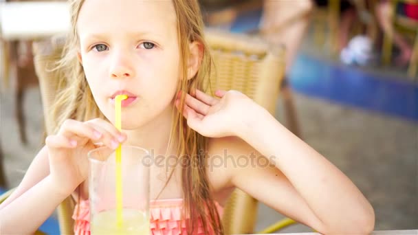 Портрет милої маленької дівчинки, що сидить за обіднім столом і п'є свіжий сік — стокове відео
