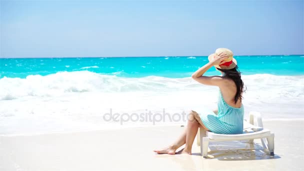 Молода красива жінка на тропічному пляжі з білим піском. Вид ззаду біла дівчина в капелюсі на фоні моря — стокове відео
