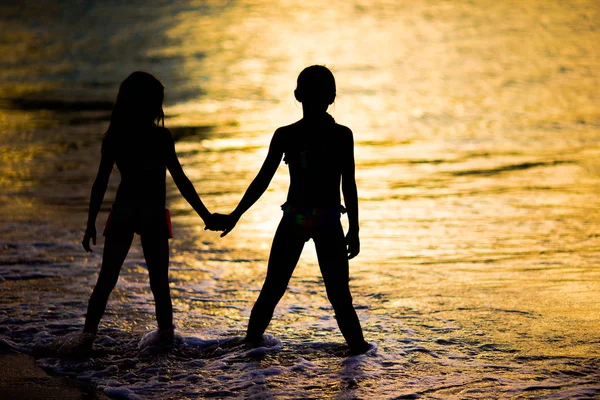 Adorable little girls on the beach with beautiful colorful sunset — Stock Photo, Image