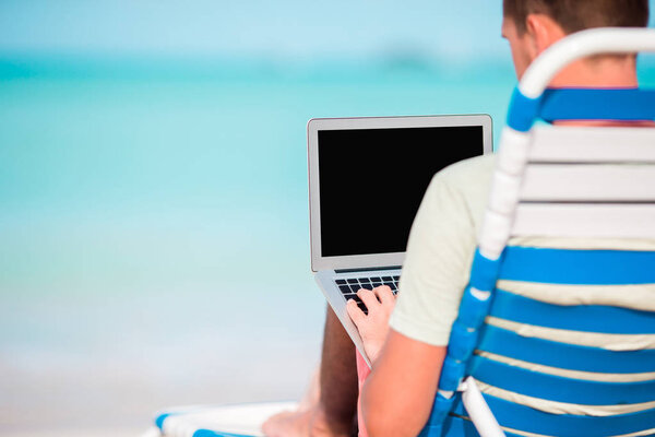 Молодой человек с ноутбуком на тропическом карибском пляже. Закрыть компьютер в руках мужчин
