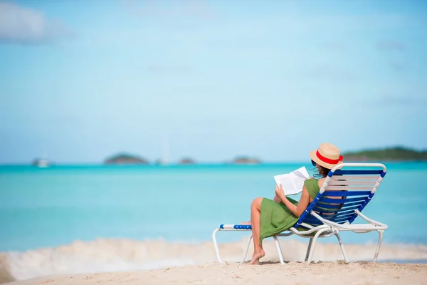 若いです女性読書本で日向ぼっこ中に熱帯の白いビーチ — ストック写真