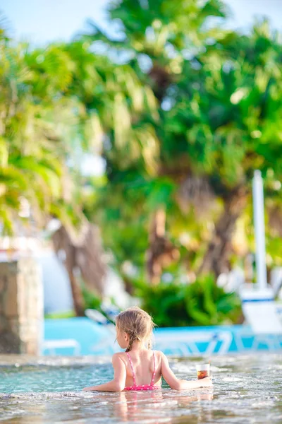 Little girl in outdoor swimming pool enjoy her vacation with tasty drink — Stock Photo, Image
