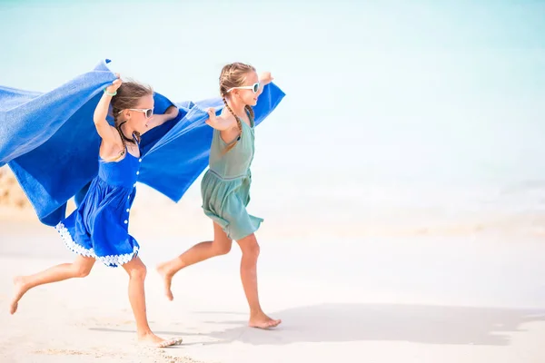 Dziewczynki bawią się biegając z ręcznikiem i ciesząc się wakacjami na tropikalnej plaży z białym piaskiem i turkusową wodą oceanu — Zdjęcie stockowe