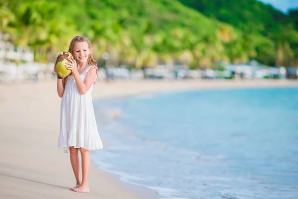 Kleines entzückendes Mädchen mit großer Kokosnuss am Strand — Stockfoto