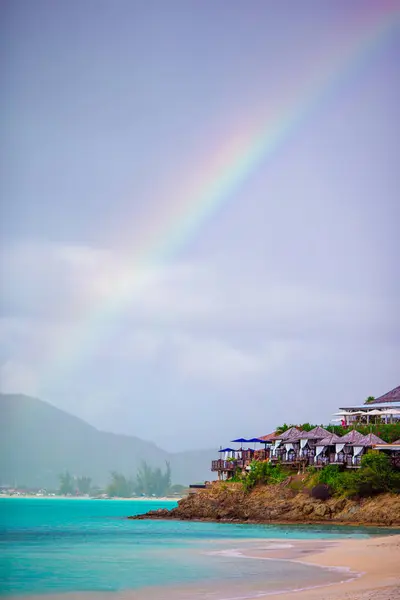 Tropical beach with turquoise water in the ocean, white sand and colorful rainbow over the sea — Stock Photo, Image