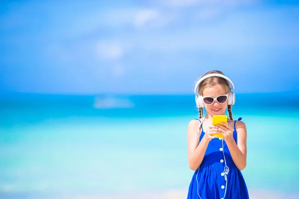 Meisje luisteren naar muziek op koptelefoon op het strand — Stockfoto