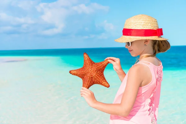 Adorable fille avec des étoiles de mer sur la plage. Étoile de mer dans les mains d'une petite fille — Photo