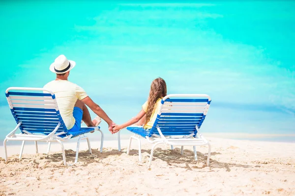 Ojciec i córka ręce do góry na plaży siedzi na szezlong — Zdjęcie stockowe