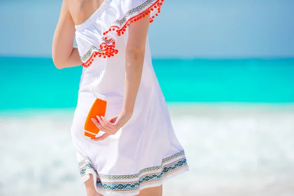 Крупный план бутылка крема для загара в женских руках на пляже — стоковое фото