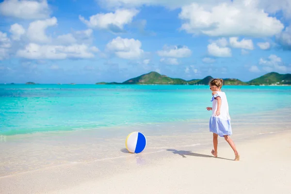 Очаровательная маленькая девочка играет с мячом на пляже. Детский летний спорт на открытом воздухе на Карибском острове — стоковое фото