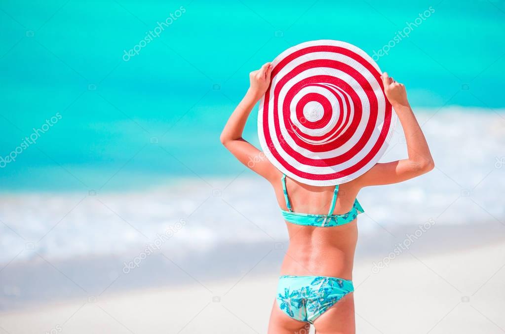 Adorable little girl in big hat on white sand Caribbean beach