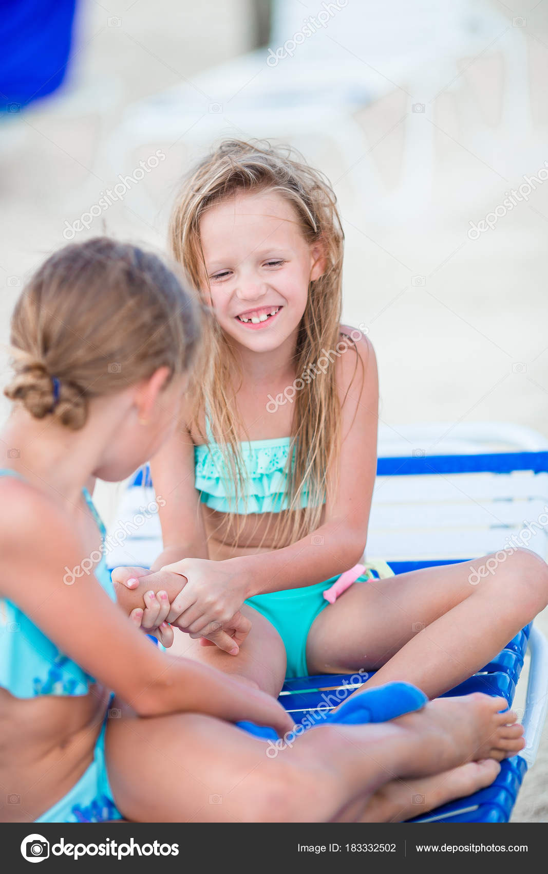 Little girls having fun at tropical beach playing together on sunbed —  Stock Photo © d.travnikov #183332502