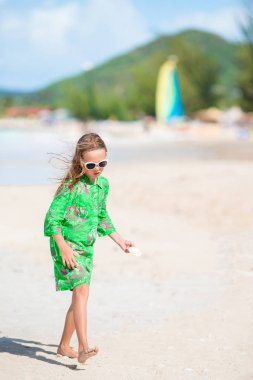 Tropik sahilde elinde seashell ile küçük şirin kız. Sevimli küçük kız kabukları ile kumsalda oynarken