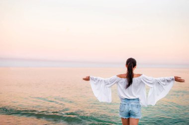 Gün batımında sahilde genç bir kadın.